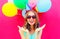 Portrait happy smiling young woman in a birthday cap is having fun over an air colorful balloons pink