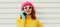 Portrait of happy smiling young woman calling on smartphone wearing a colorful pink knitted hat, yellow sweater