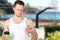 Portrait of a happy sports man standing near sport field with a mobile phone outdoors