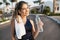 Portrait happy sunny morning of sportive active young woman smiling to camera with bottle of water on street of tropical