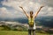 Portrait of happy traveler woman with backpack standing on top o