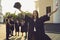 Portrait of a happy university graduate who raises her hands with a diploma and a hat.