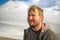 Portrait of a happy unshaven man in the mountains. Tourist climber on the background of mountains