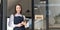 Portrait of a happy waitress standing at restaurant entrance. Portrait of mature business womanattend new customers in