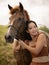 Portrait of happy woman and brown horse. Asian woman hugging horse. Romantic concept. Positive emotions. Human and animals