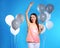 Portrait of happy woman with champagne in glass party balloons on color background