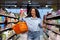 Portrait of a happy woman shopper in a supermarket, a Hispanic woman with a basket of goods smiles with pleasure and
