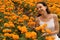 Portrait of happy woman smiling in marigold flower and enjoying the fragrance. Marigold valley in Bali