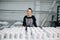 Portrait of a happy woman standing behind rows of blank cups in a workshop