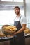 Portrait of happy worker holding basket of bread