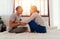 Portrait of happy young adult Asian couple tickling each other on bed together in bedroom interior scene. 30s candid