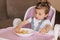 Portrait of happy young baby girl in high chair eating exotic fruits. Healthy nutrition for kids