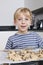 Portrait of happy young boy in front of baking tray of cookies