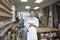 Portrait of a happy young craftsman standing with arms crossed in workshop