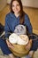 Portrait of happy young domestic woman in pajamas posing with straw basket for linens storage