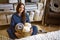 Portrait of happy young domestic woman in pajamas posing with straw basket for linens storage