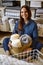 Portrait of happy young domestic woman in pajamas posing with straw basket for linens storage