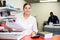 Portrait of happy young female typographer using paper cutter cutter during work in the printer shop