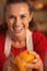 Portrait of happy young housewife removing orange peel