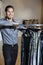 Portrait of a happy young male standing by clothes rack in fashion store