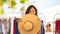 Portrait of happy young pretty woman hiding behind a big straw hat, smiling and looking away