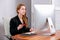 Portrait of happy young successful businesswoman at office. She sits at the table and enters credit card details on the keyboard.