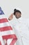 Portrait of a happy young US Navy officer saluting American flag over gray background