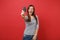 Portrait of happy young woman in casual striped clothes screaming, showing credit card on camera isolated on bright red