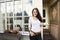 Portrait of happy young woman holding coffee cup in front of cafe