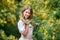 Portrait of a happy young woman with a Mimosa. A girl in a white dress is holding a branch of Mimosa.