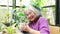 Portrait of a healthy elderly woman sitting and caring for a cactus, looking at the camera with a beautiful smile.