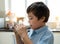 Portrait healthy school boy drinking glass of milk for breakfast, Happy child standing in kitchen drinking warm milk before go to