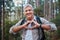 Portrait, heart and senior man in forest hiking, fitness and health support, self care hands and cardiovascular workout