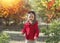 Portrait of Ñheerful and happy child,  girl in a bright red coat and gray knitted skirt plays with autumn leaves on a sunny day