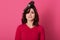 Portrait of helpless disappointed woman standing isolated over pink background in studio, looking directly at camera, having comb