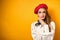 Portrait of a hesitantly frowning beautiful blonde with red lipstick, in a white blouse and a red beret with a