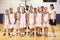 Portrait Of High School Sports Team In Gym With Coach