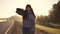 Portrait of a hipster girl in the rays of sunset. Attractive red-haired girl comes with a skateboard in her hands and