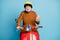 Portrait of his he nice attractive cheerful cheery glad bearded grey-haired man riding moped using device gadget