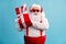 Portrait of his he nice attractive cheerful cheery glad white-haired Santa father holding in hands festal red giftbox