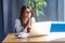 Portrait of hopeful beautiful stylish brunette young woman in glasses sitting, looking at her laptop monitor with worry face and