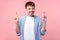 Portrait of hopeful brown-haired man with small beard and mustache in casual shirt crossing fingers. isolated on pink background