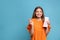 Portrait of hopeful young woman with lottery ticket on light blue background