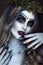 Portrait of a horrible scary Corpse Bride in wreath with dead flowers, halloween makeup and long manicure.Design of