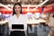 Portrait of hostess wearing uniform with tablet in shopping mall. Space for text