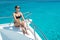 Portrait of hot attractive woman sitting on bow of yacht in bikini