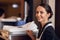 A portrait of a housekeeping lady with a cleaning cart and cleaning supplies, looking at the camera and posing