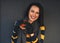 Portrait of hungry happy woman wearing casual sweater, eatting fast food burger while posing at terrace on gray background. Female