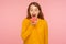 Portrait of hungry slim ginger girl in sweater standing with opened mouth to bite doughnut, eating pink donut with happy