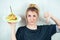 Portrait of a hungry, young and beautiful blonde holding a burger cheeseburger on a plate in a black T-shirt and